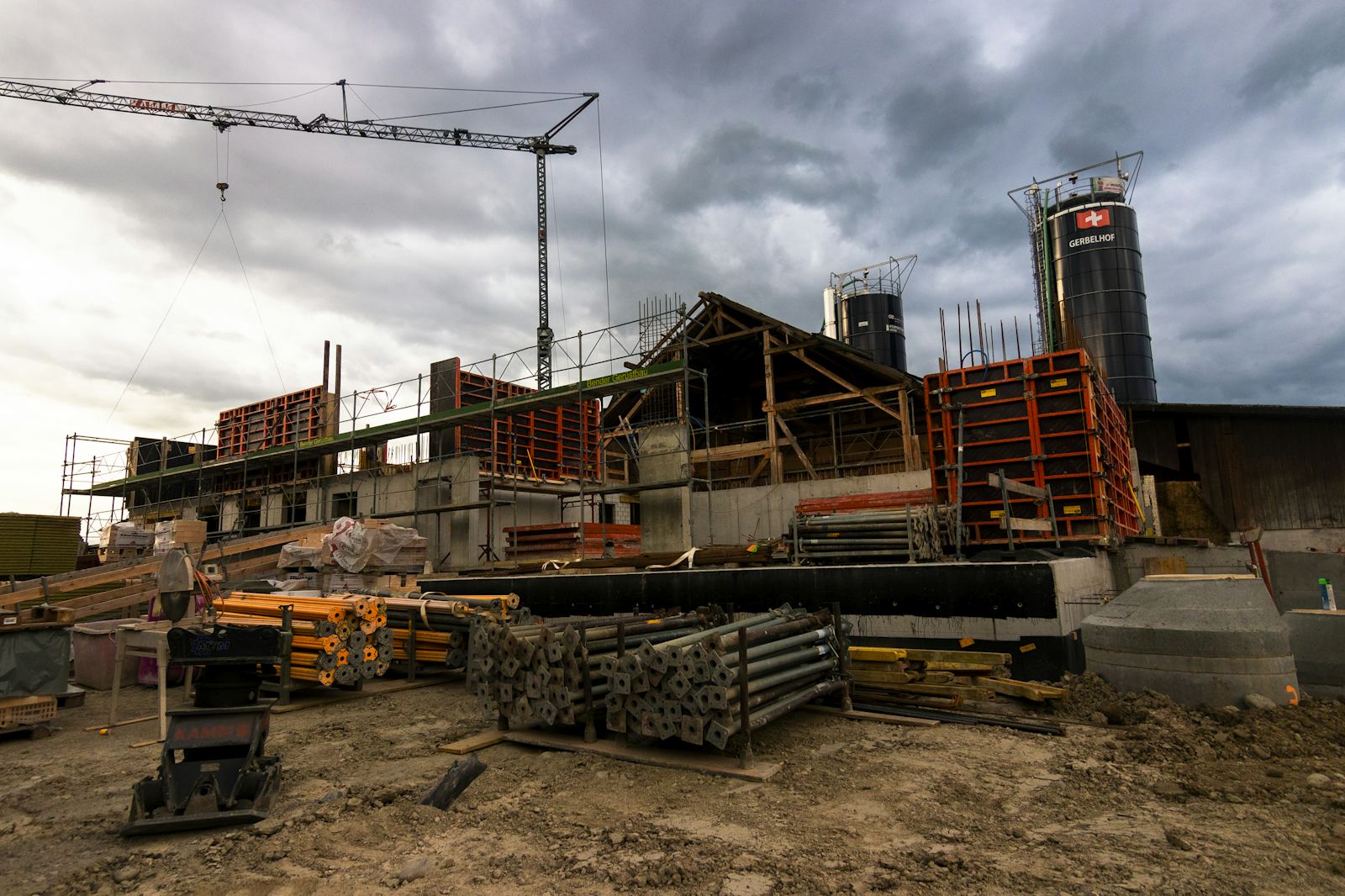 Construction site with stacked formwork, props and a tower crane