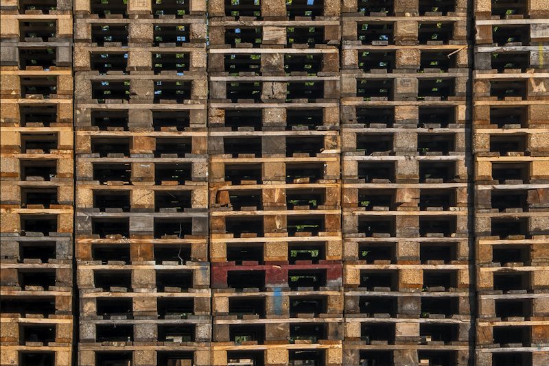 A tall stack of wooden pallets